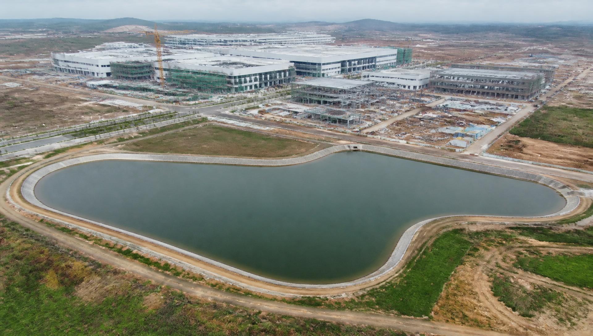 Aerial view of a large industrial site with a water reservoir and factory buildings